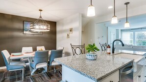A modern kitchen with a granite countertop, stainless steel appliances, and pendant lighting.