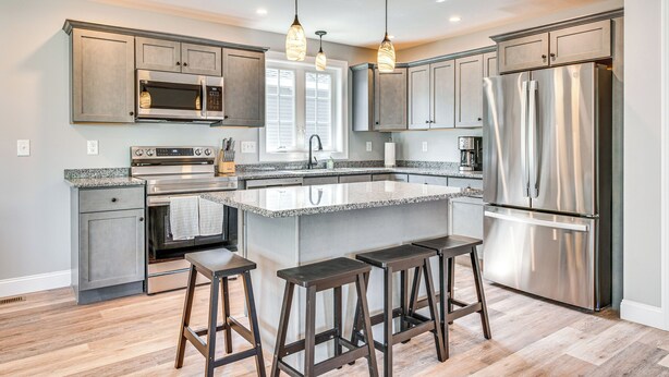 A modern kitchen with granite countertops, stainless steel appliances, and bar stools. - Walk to Beaches & Parks: Home w/ Deck in Laconia (Laconia)