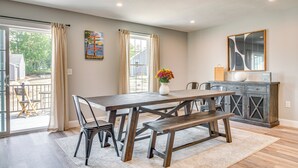 A dining area with a wooden table, benches, and chairs. There is a vase with flowers on the table. - Walk to Beaches & Parks: Home w/ Deck in Laconia (Laconia)
