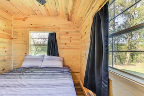 A wooden cabin room with a bed, a window, and curtains. - Riverfront Cabin Near Yellowstone Lake State Park (Blanchardville)