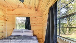 Ein Zimmer in einer Holzhütte mit Bett, Fenster und Vorhängen.