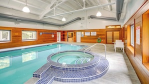 Ein Hallenbad mit Whirlpool, Holzwänden und einer Decke mit sichtbaren Balken und Leuchten.