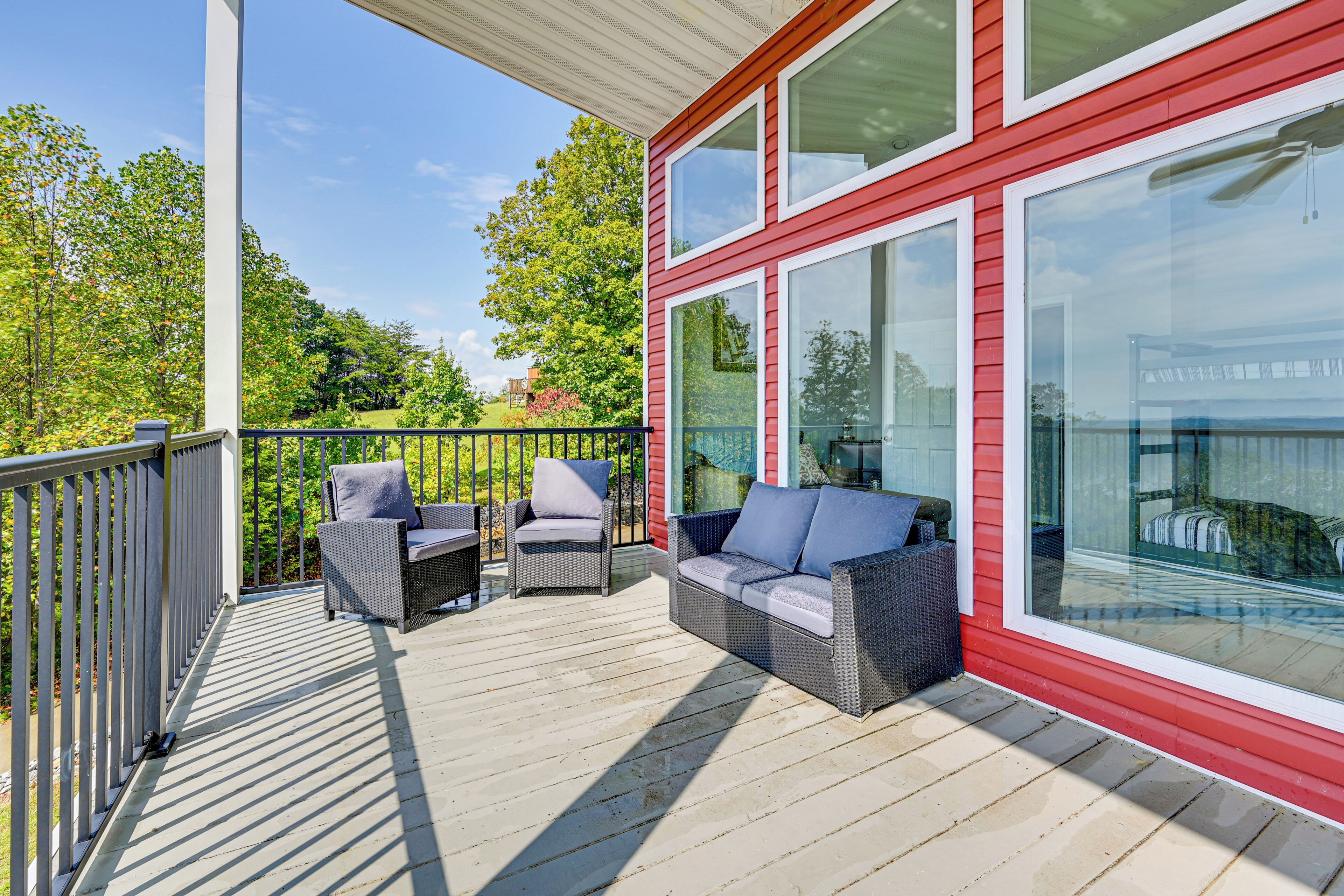 A covered outdoor deck with wicker furniture and large windows.
