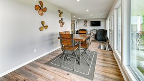Un comedor con una mesa y sillas de madera, un tapete estampado y ventiladores de pared decorativos.