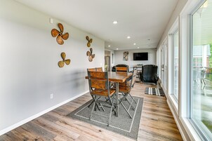 Un comedor con una mesa y sillas de madera, un tapete estampado y ventiladores de pared decorativos.
