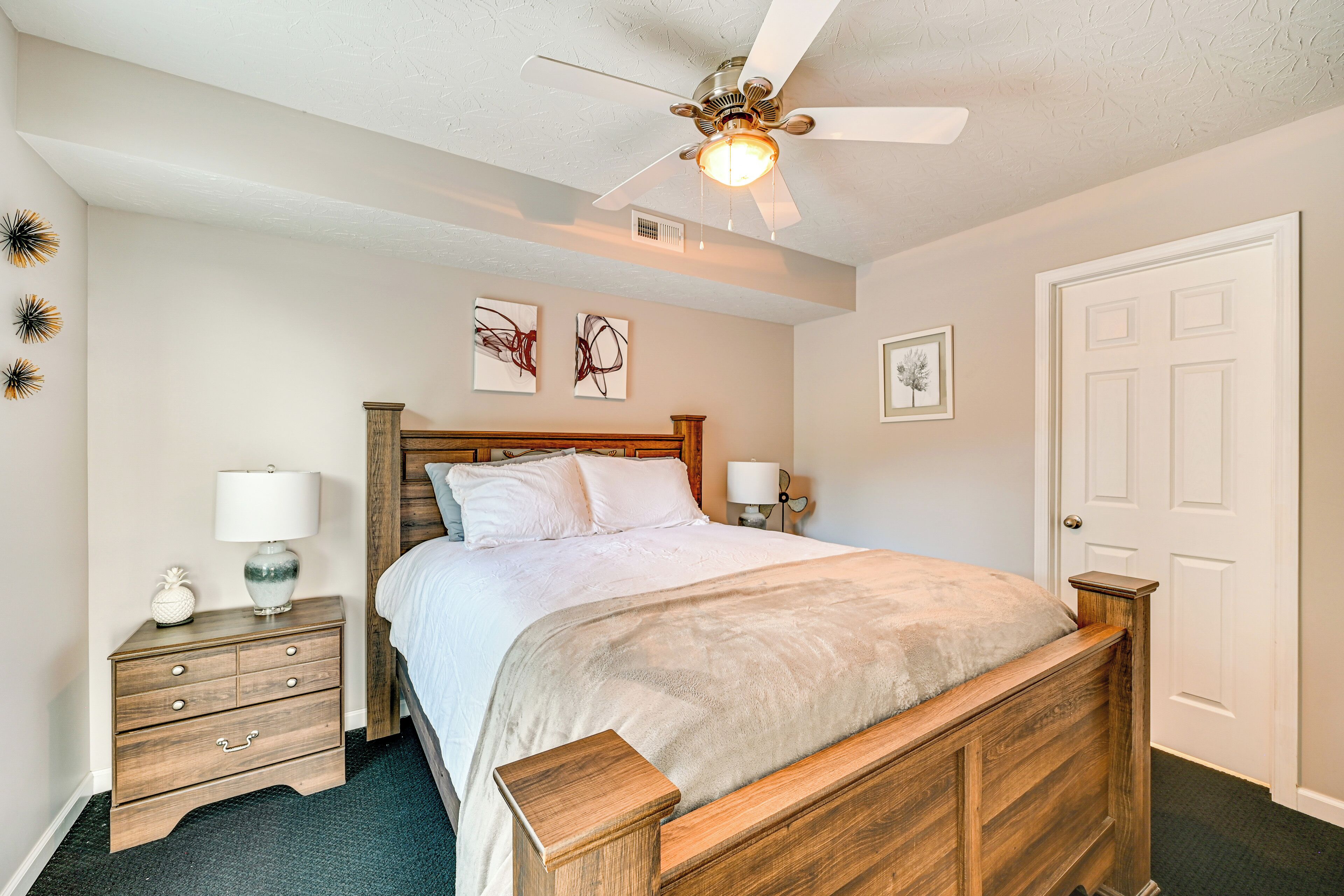 A bedroom with a wooden bed, a nightstand with a lamp, and a ceiling fan.