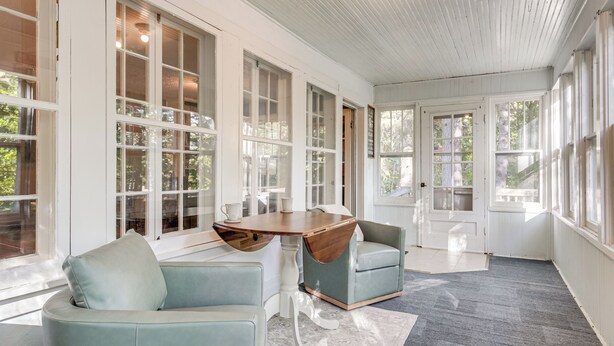 A spacious room with large windows, a wooden table, and two light blue chairs. - Hillside Home on 4 Wooded Acres by Sunday Lake (Wakefield)