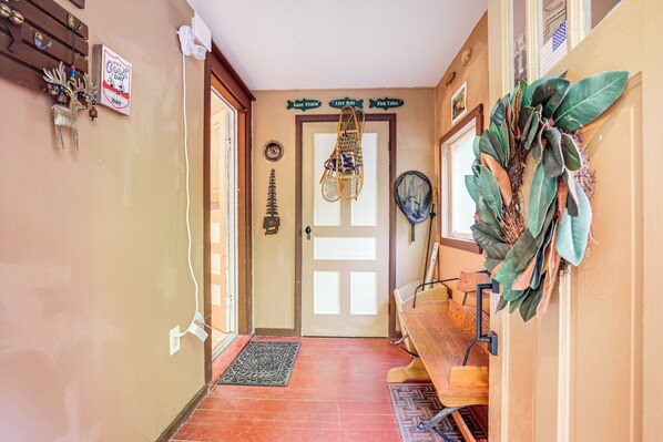 A hallway with a wooden bench, a door with a sign above it, and a wall-mounted fan.
