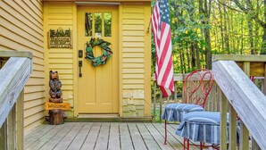 A yellow building with a wooden deck, a welcome sign, a wreath, and an American flag. - Hillside Home on 4 Wooded Acres by Sunday Lake (Wakefield)