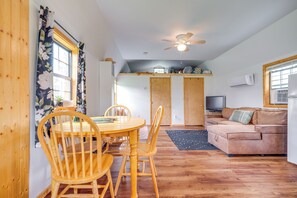 Una sala de estar acogedora con una mesa de comedor de madera, sillas, un sofá y un ventilador de techo.