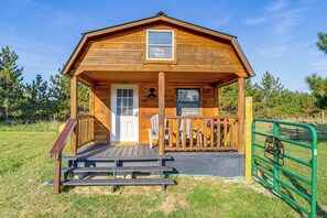 A wooden cabin with a porch, a door, and a window. - 9 Mi to Lake Michigan: Secluded Cabin Getaway (Central Lake)