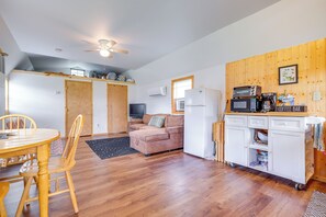 Un espacio habitable compacto con kitchenette, un sofá, una mesa de comedor con sillas y un ventilador de techo.