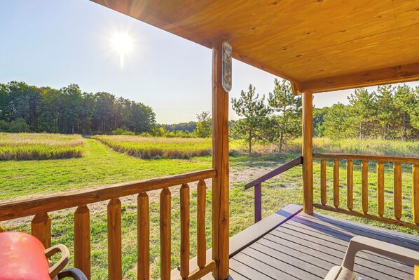 Una terraza de madera con vista a un campo cubierto de hierba y árboles.