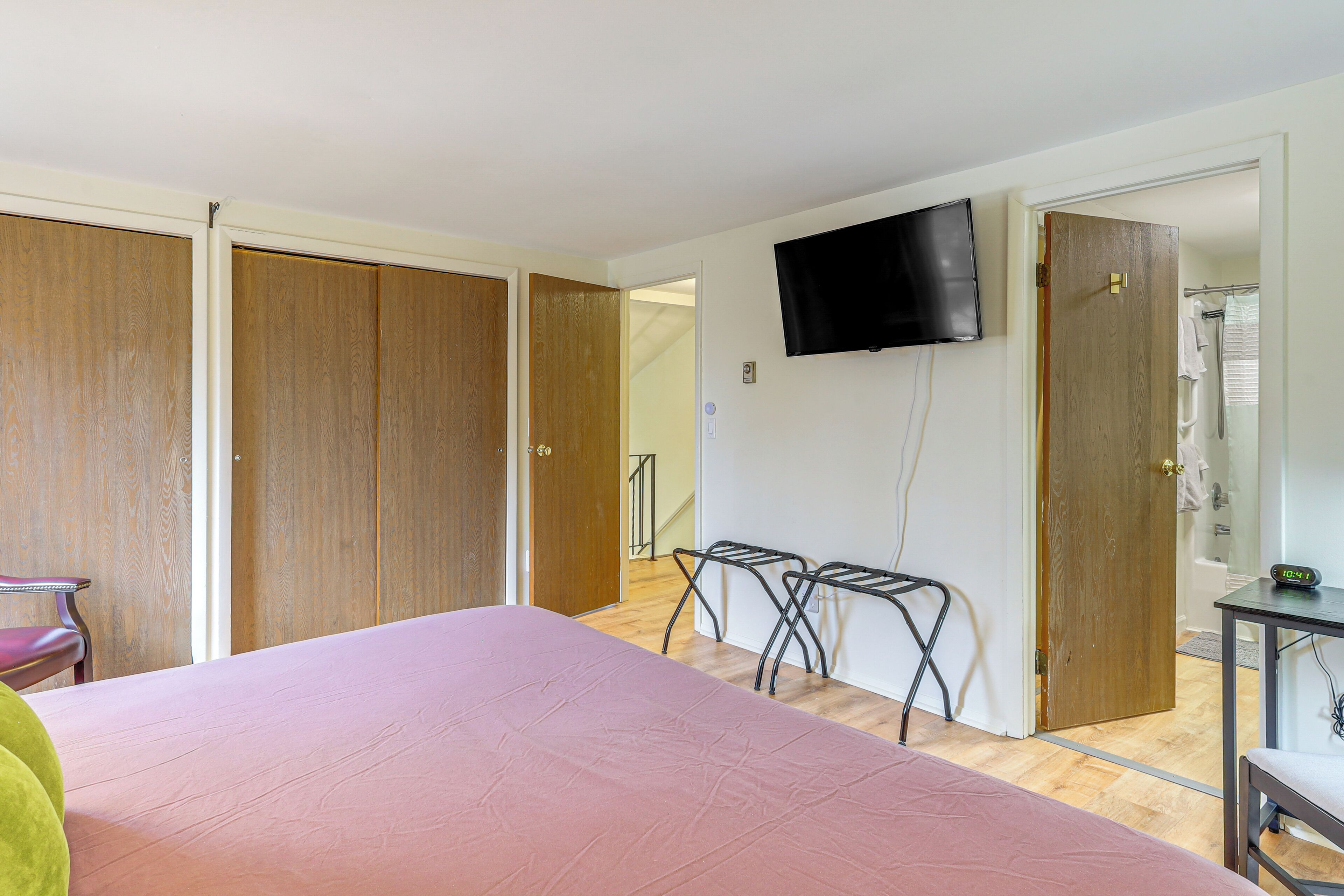 A bedroom with a bed, a TV, a wooden wardrobe, and a bathroom visible through an open door.