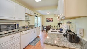 A modern kitchen with white cabinets, a microwave, a toaster, and a dining area with a table and chairs.