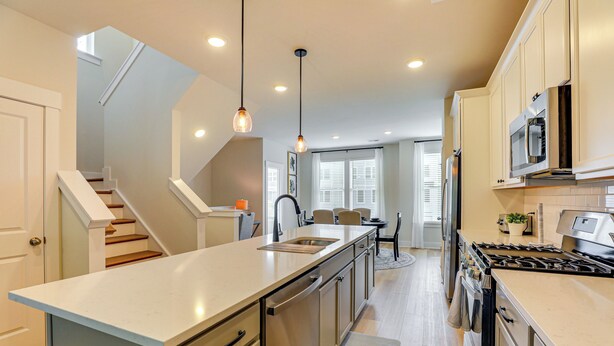 A modern kitchen with a central island, stainless steel appliances, and a staircase leading to another level. - 13 Mi to Dtwn Charleston: Quiet Townhome (Hanahan)