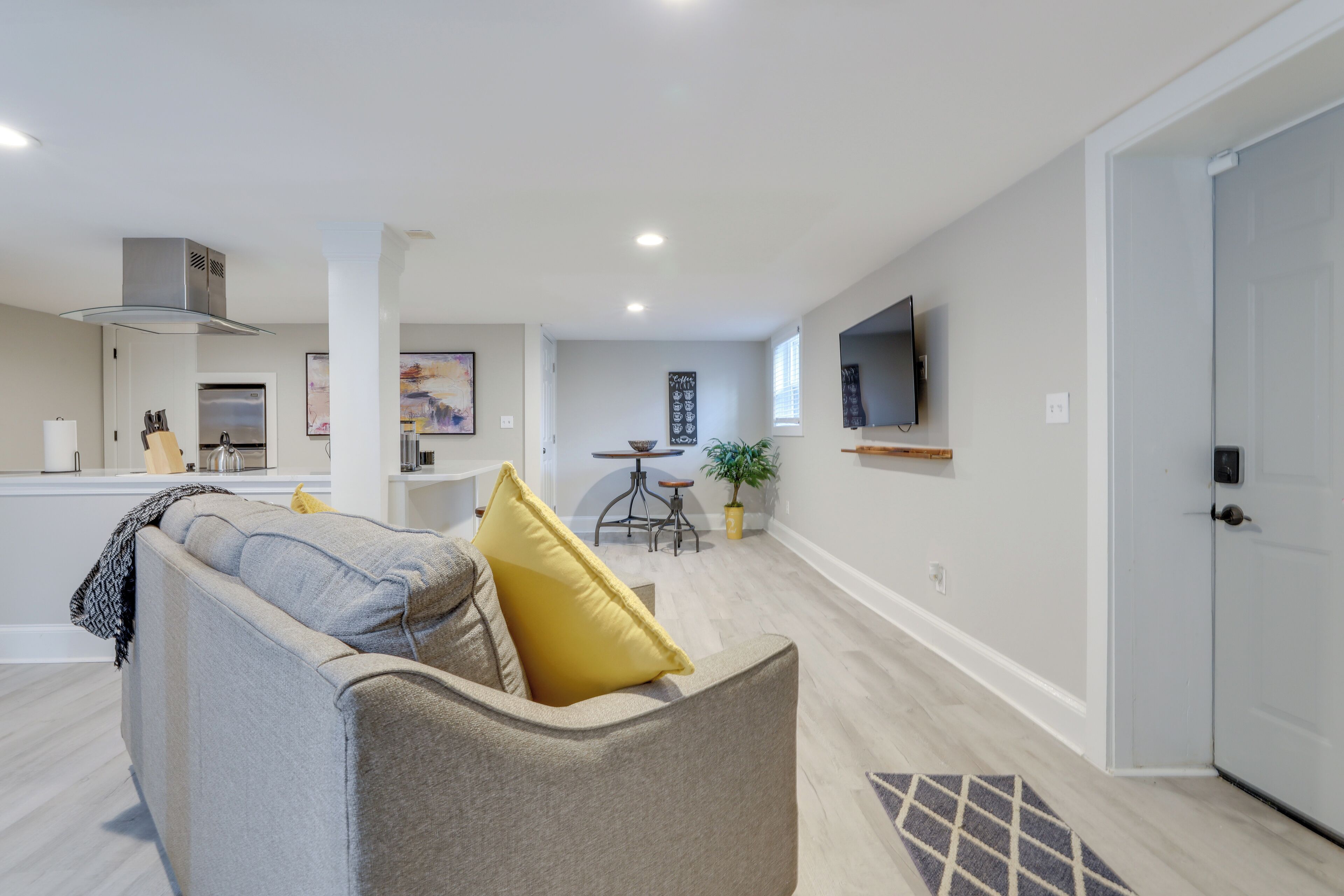 A modern living room with a sofa, a coffee table, and a TV mounted on the wall.