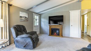 A living room with a fireplace, a black leather recliner, and a television. - Lake Views & Fireside Bliss: Cecil Cottage w/ Yard (Cecil)