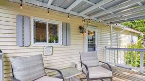 A porch with two chairs and a small table, a sign reading "WELCOME TO THE BACKYARD," and a view of a house with a porch railing. - Lake Views & Fireside Bliss: Cecil Cottage w/ Yard (Cecil)