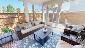 Un patio abrité avec un canapé en osier, une table basse et des chaises en osier.