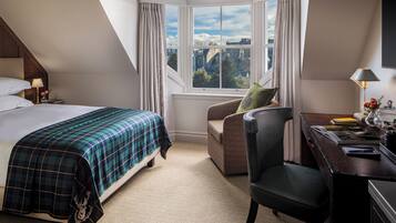 Una habitación de hotel con cama, escritorio, silla y ventana con vista a la ciudad.
