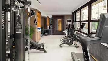 A modern gym with a treadmill, weight machines, and a mirror.