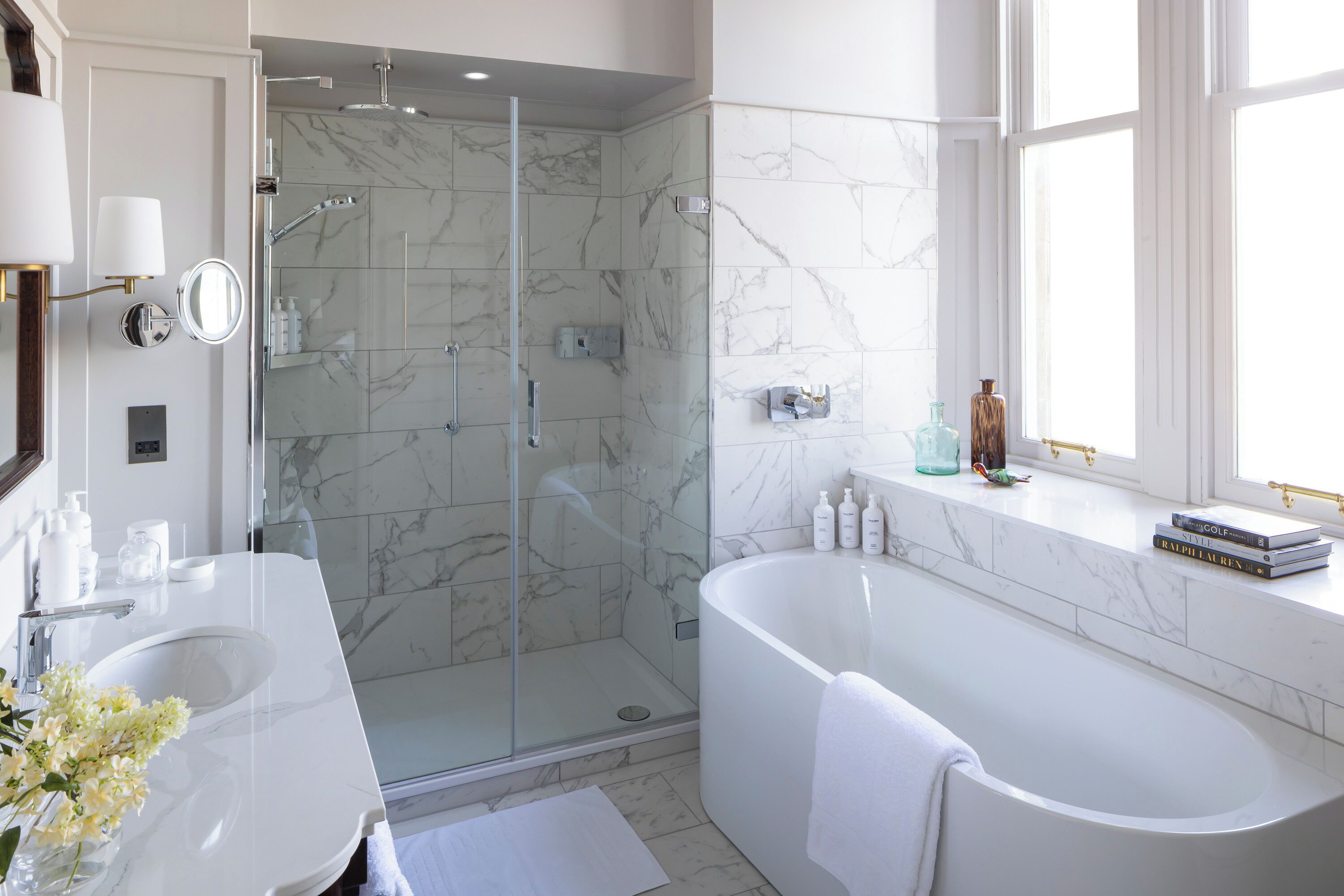 A modern bathroom with a glass-enclosed shower, a freestanding bathtub, and a vanity with a large mirror.