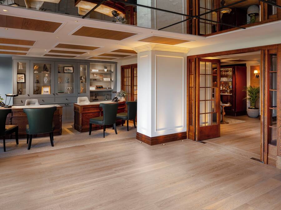 A spacious living area with a high ceiling, wooden flooring, and a built-in cabinet with glass doors displaying various items.