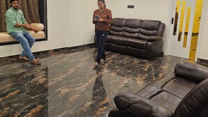 Una sala de estar moderna con suelo de mármol, ventilador de techo, sofá y sillón reclinable.