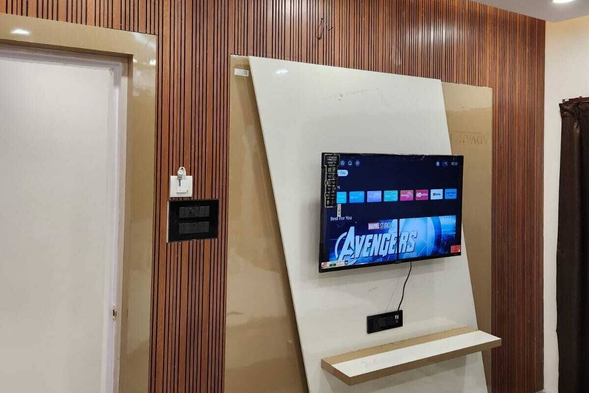 A modern room with a mounted TV displaying 'Avengers' on the wall, wooden paneling, and a marble floor.