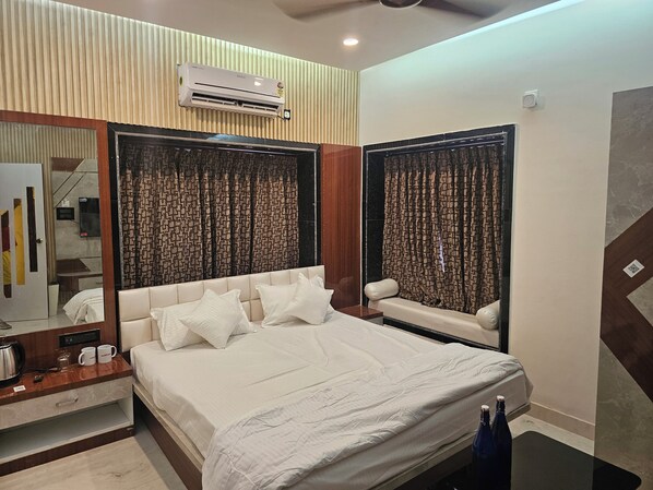 A modern bedroom with a large bed, a bedside table with a kettle, and a mirror. - LUXE LAGOON (Barasat)