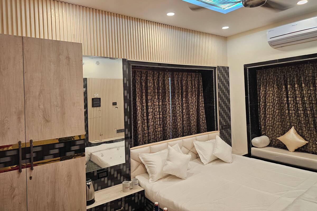 A modern hotel room with a large bed, a vanity with a mirror, a wardrobe, and a ceiling fan.