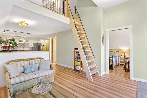 A spacious living area with a wooden staircase, a sofa, a coffee table, and a bookshelf. - Hadley Point Hideaway, Quiet & Peaceful (Bar Harbor)