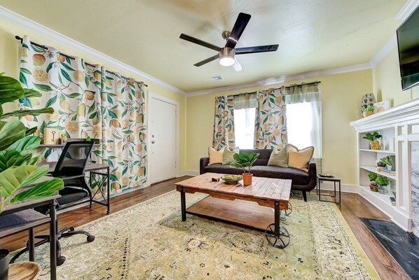 A living room with a ceiling fan, a sofa, a coffee table, and a fireplace.
