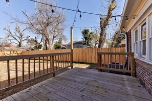 Une terrasse en bois avec une rambarde, un mur en briques et une guirlande lumineuse.
