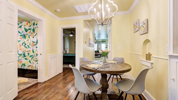 A dining area with a round table, four chairs, a chandelier, and a hallway leading to another room. - Lemonade Lodge (Oklahoma City)