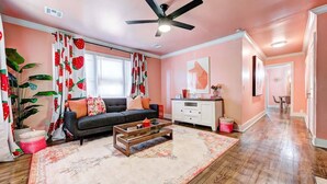 A living room with a sofa, coffee table, and curtains with a fruit pattern. - Strawberry Lodge-adorable duplex in central NW OKC (Oklahoma City)