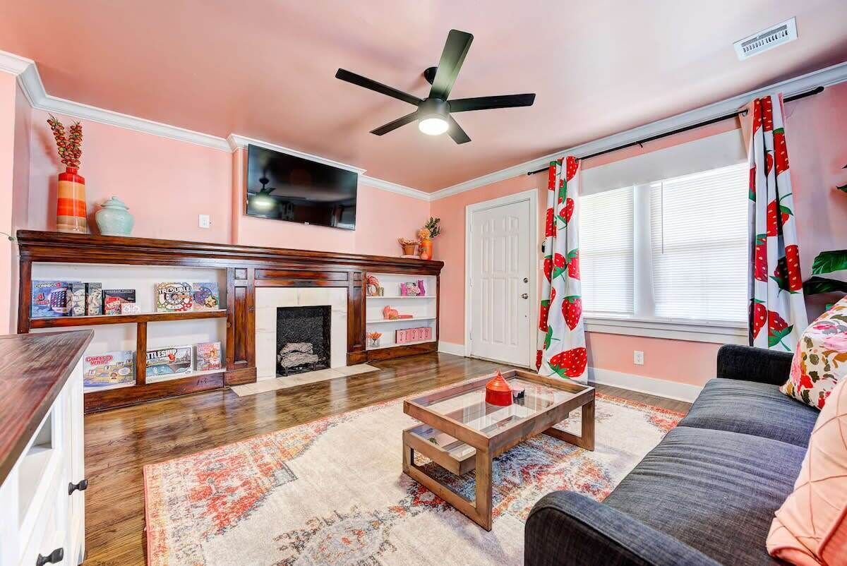 A living room with a fireplace, a television, a ceiling fan, and a sofa.