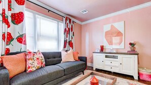 Una sala de estar con un sofá, una mesa de centro, un armario blanco y una ventana con cortinas.