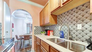Una cocina con armarios de madera, un lavamanos de acero inoxidable y un salpicadero con diseño.