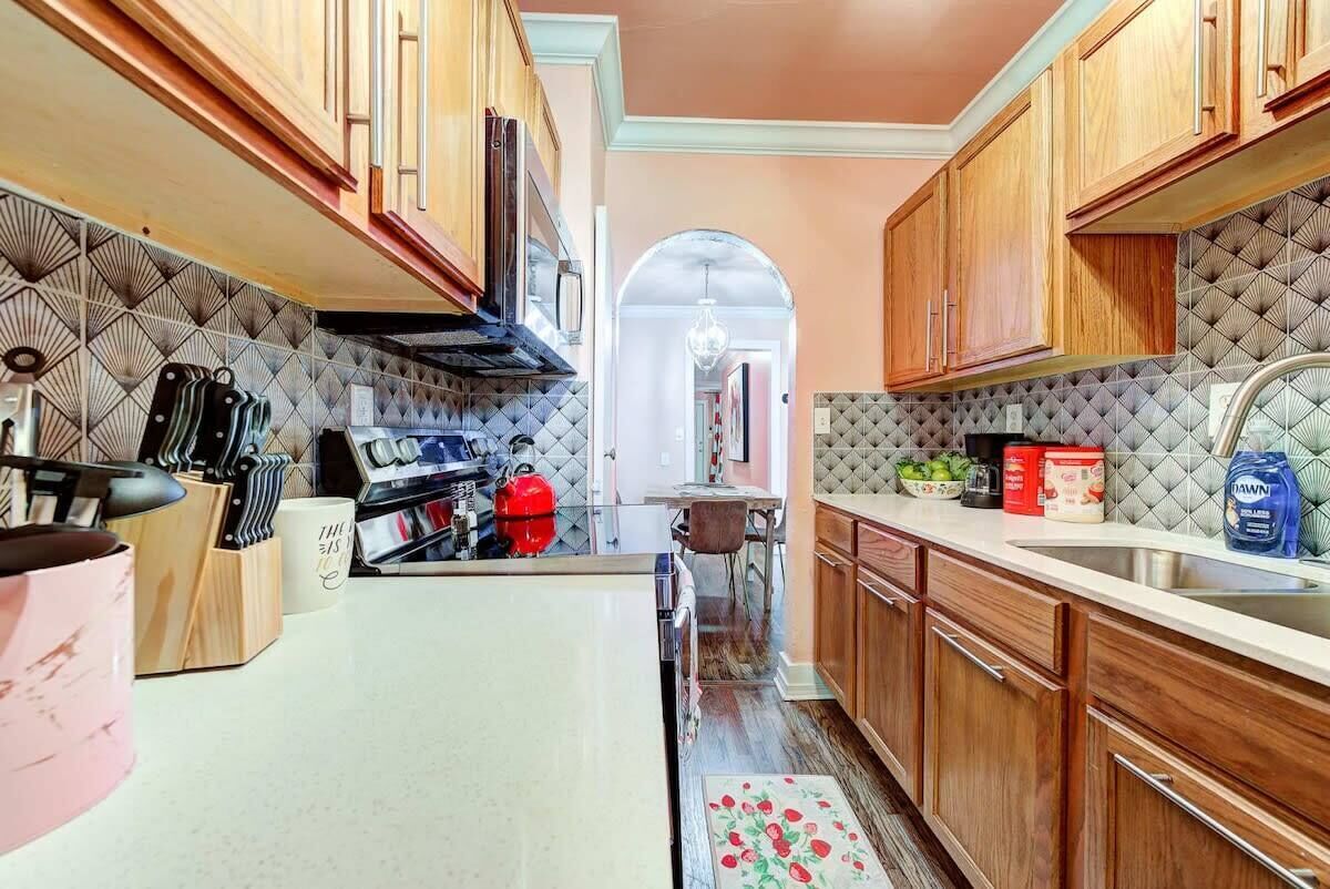 Una cocina con armarios de madera, salpicadero de azulejos y una isla central.