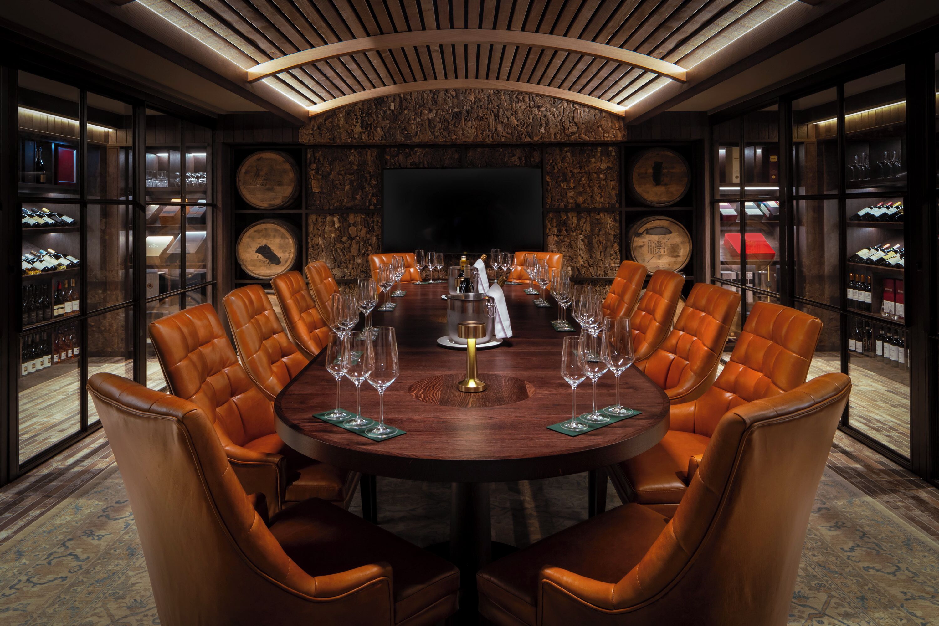 Une salle de conférence équipée d’une table ronde, de fauteuils en cuir et d’un grand écran.