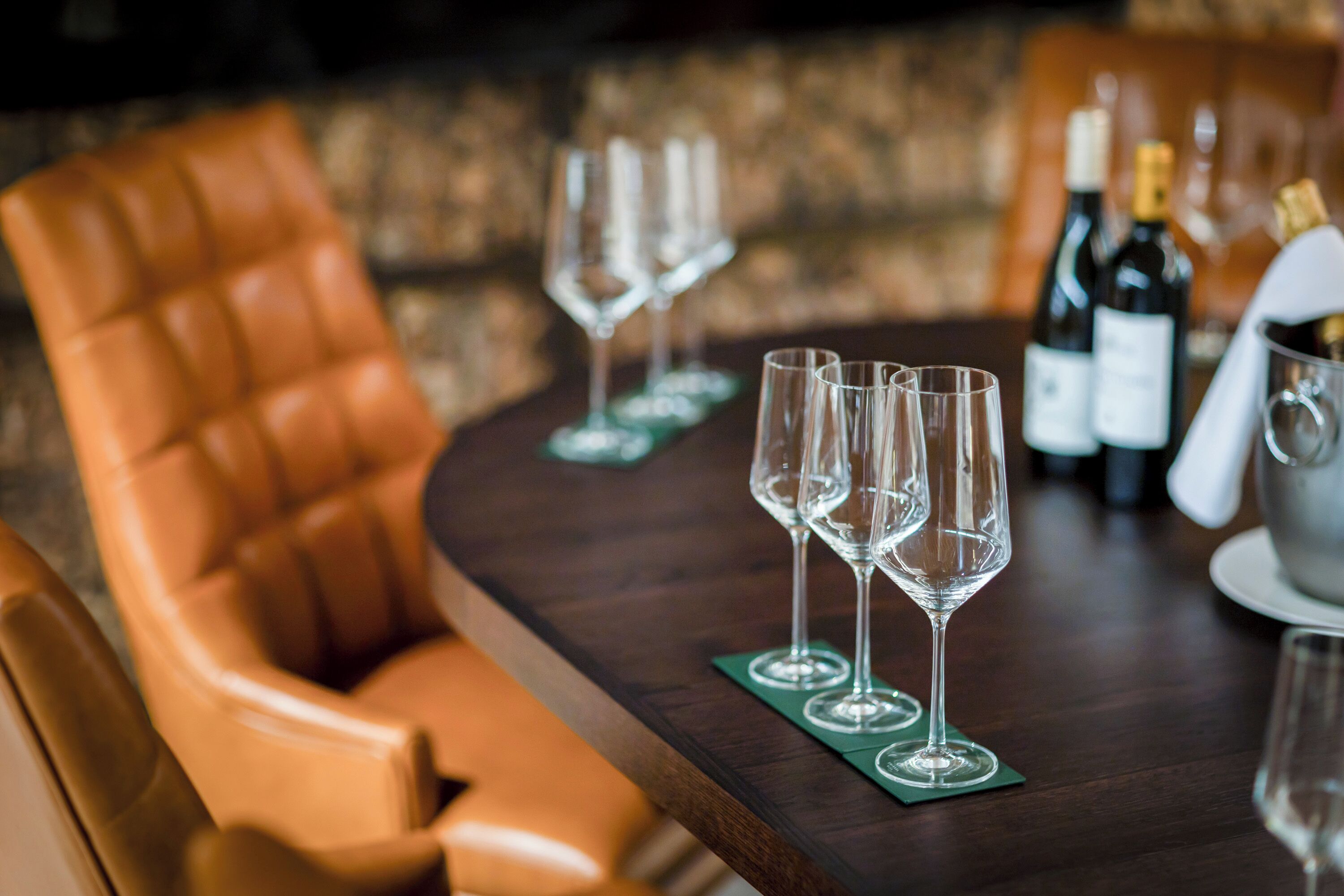 A round table with four wine glasses and a bottle of wine.