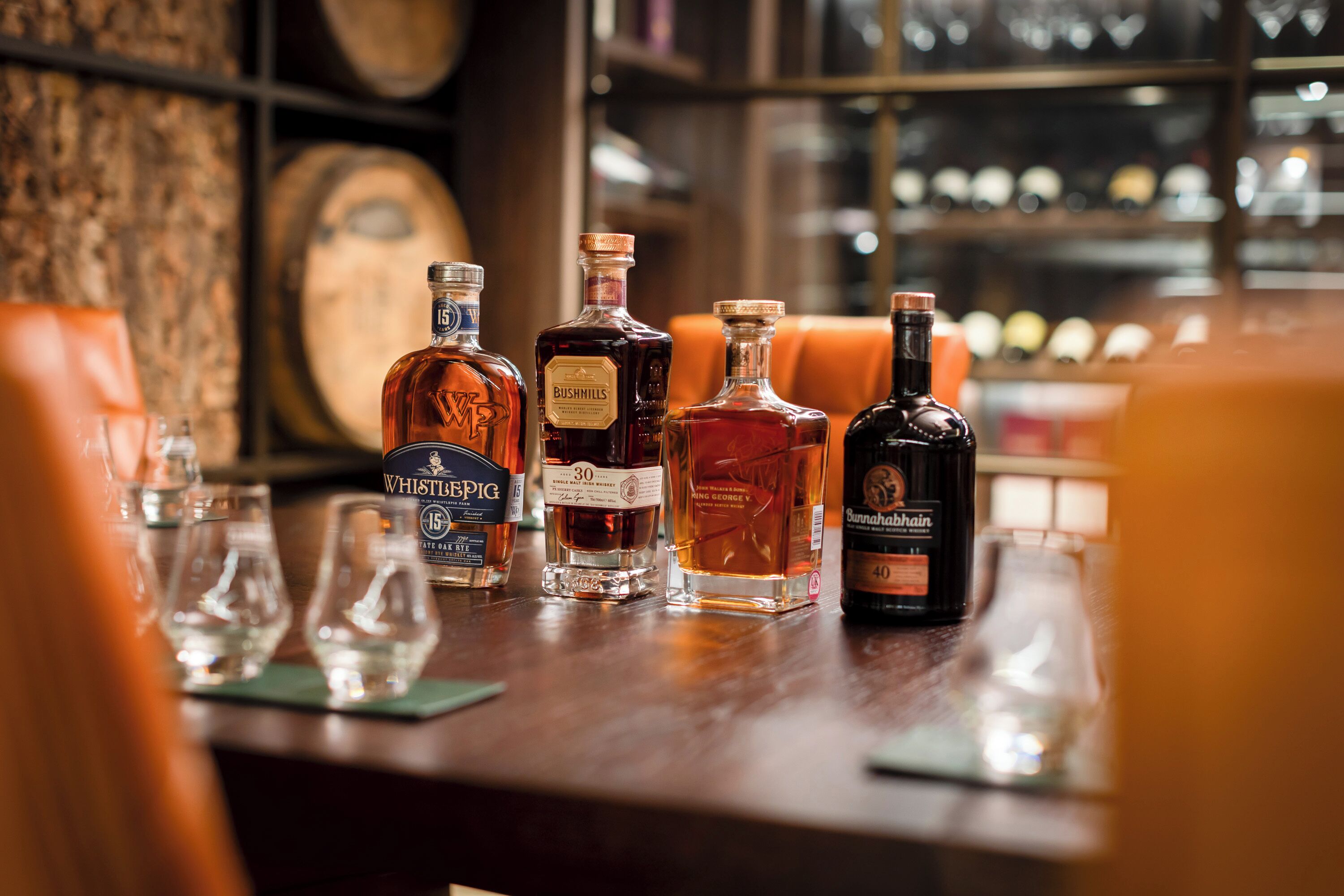 A bar with various liquor bottles and glasses on a wooden counter.