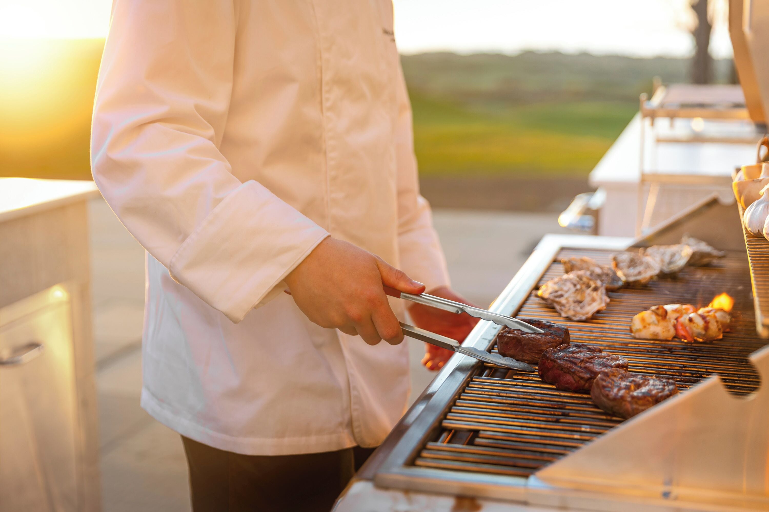 A person grilling meat on an outdoor grill.