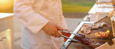 A person grilling meat on an outdoor grill.