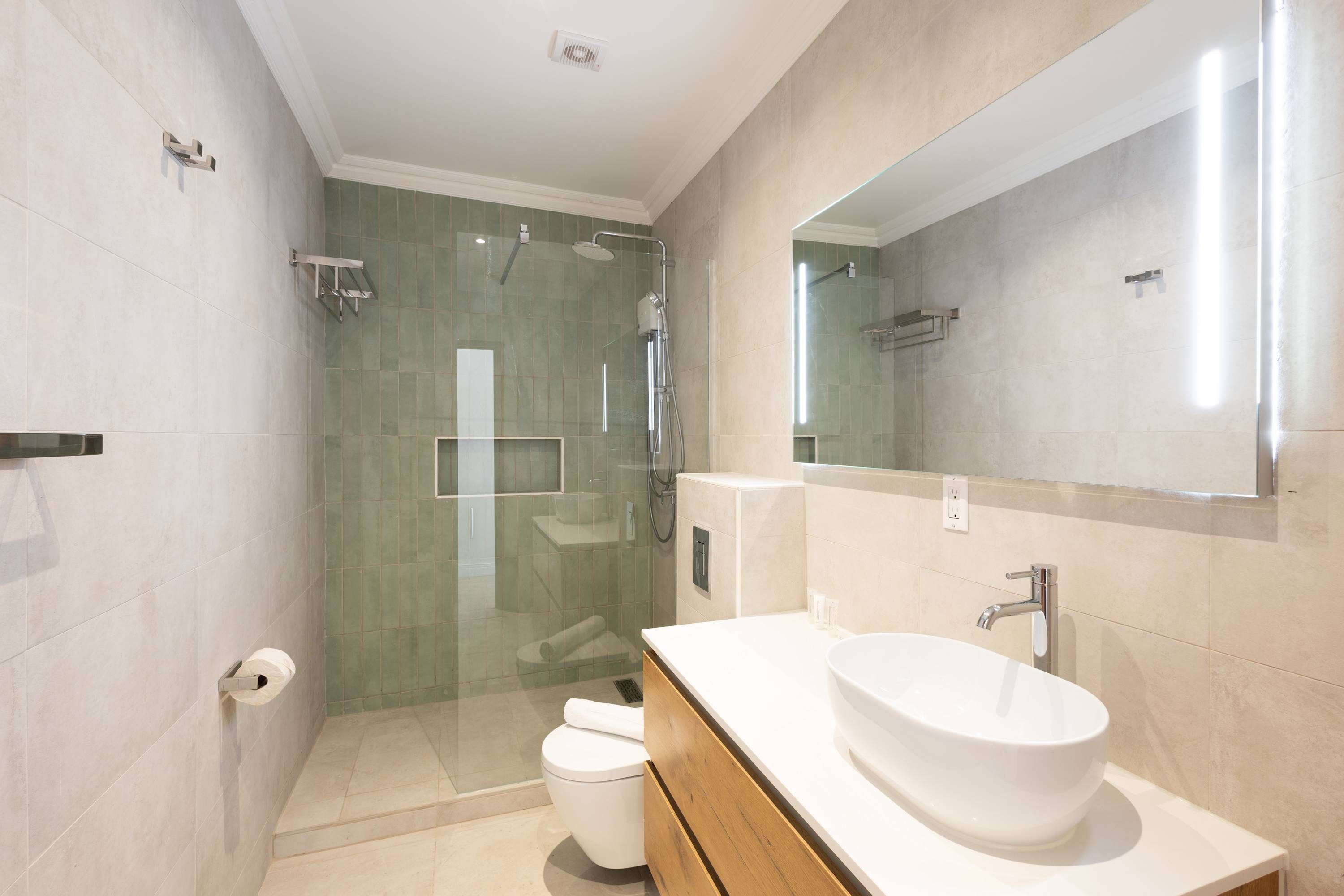 A modern bathroom with a glass-enclosed shower, a white sink, and a large mirror.