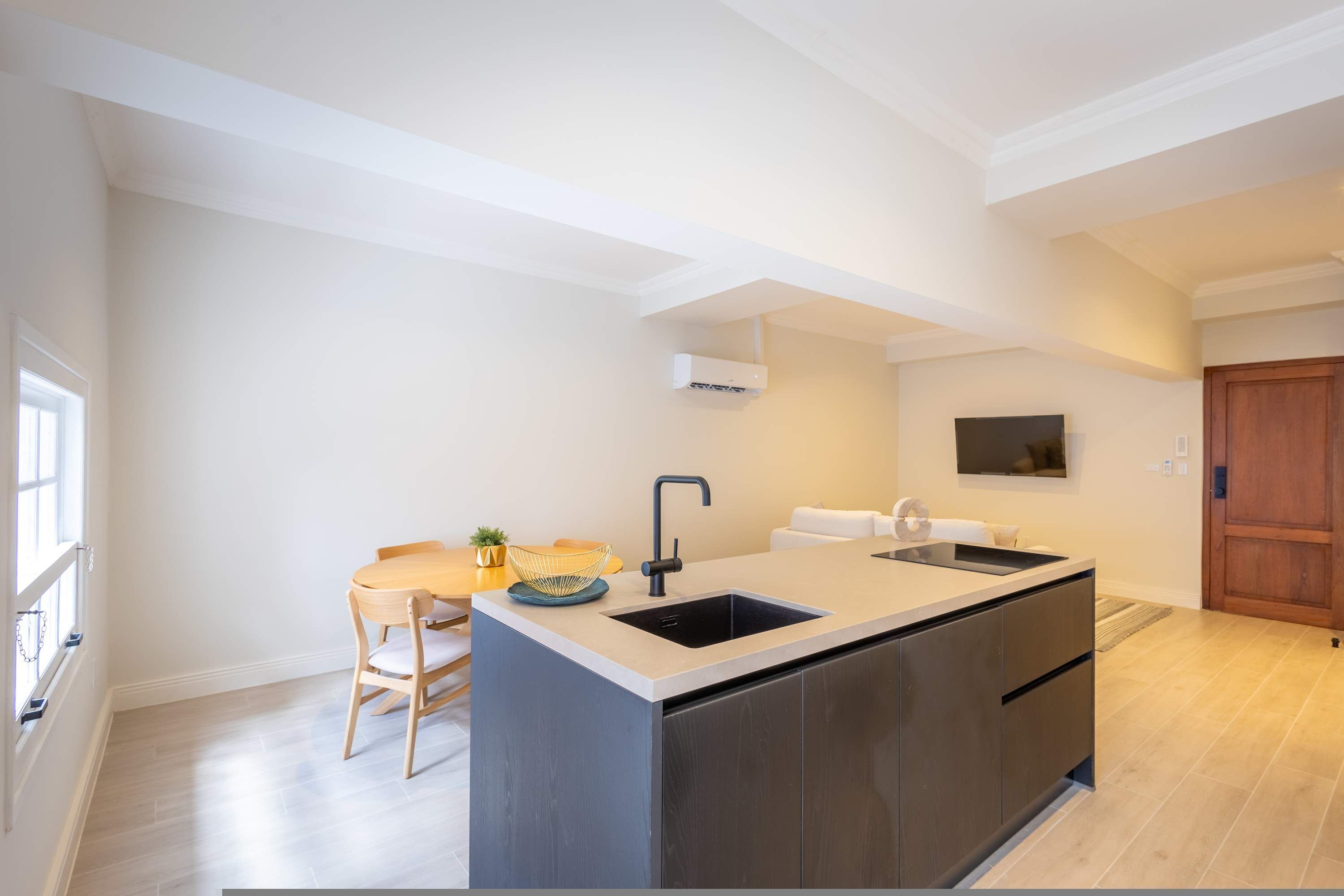 Una cocina moderna con una isla central, electrodomésticos integrados y un comedor con mesa y sillas.