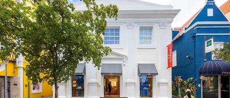 A building with a white facade, a blue corner, and a bench in front.