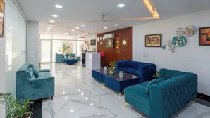 A modern lobby with teal sofas, a reception desk, and a marble floor. - Park Pacific By Saavi Hotel (Gurugram)